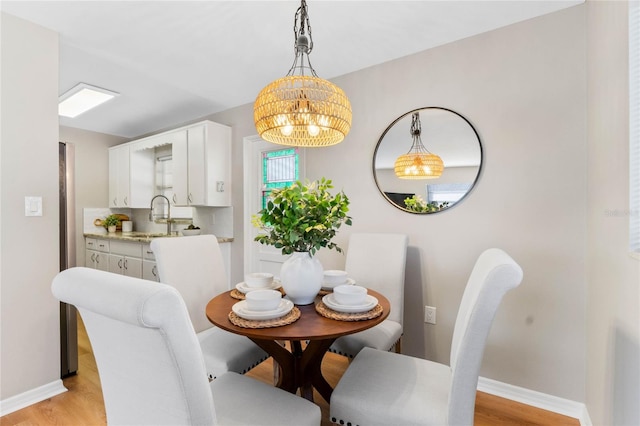 dining room with an inviting chandelier, light hardwood / wood-style floors, and sink