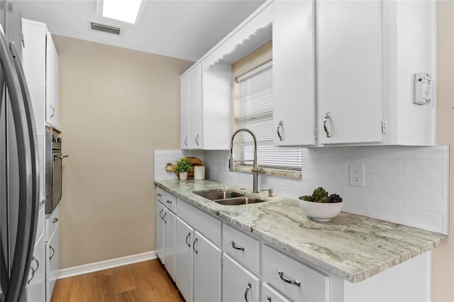 kitchen featuring white cabinetry, sink, and stainless steel fridge