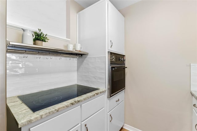 kitchen with tasteful backsplash, light stone countertops, black appliances, and white cabinets