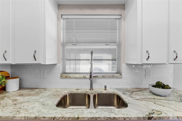 kitchen featuring white cabinetry, sink, decorative backsplash, and light stone counters