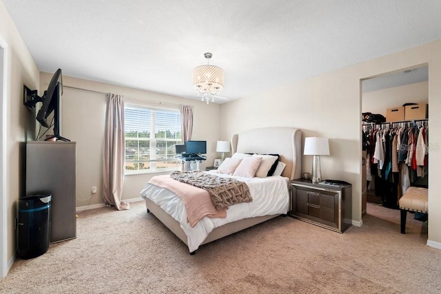 carpeted bedroom featuring a walk in closet, a notable chandelier, and a closet