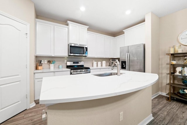 kitchen featuring white cabinetry, stainless steel appliances, and a center island with sink