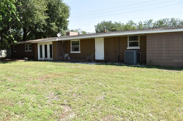 423 Longfellow Blvd, Lakeland, FL 33801 - rear view of house with central AC, french doors, a yard, and a chimney