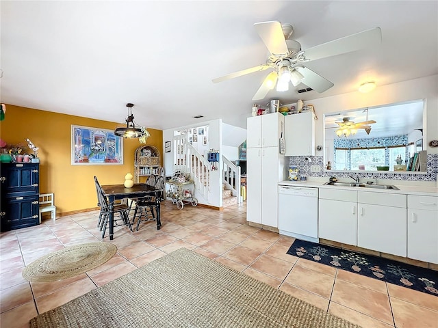 kitchen featuring light tile patterned floors, sink, dishwasher, white cabinets, and decorative light fixtures