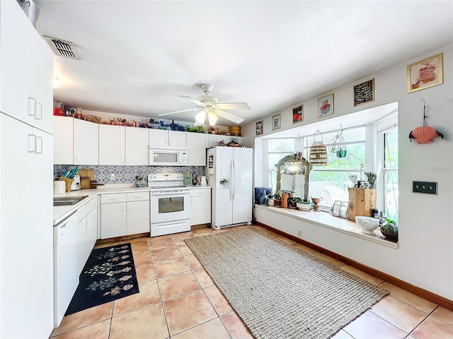 kitchen with tasteful backsplash, white appliances, light tile patterned flooring, and white cabinets