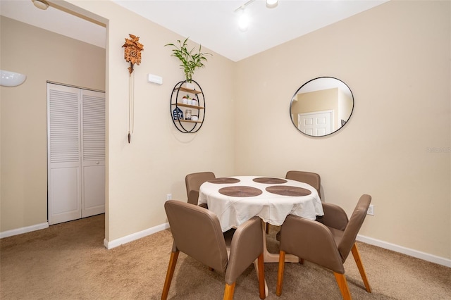 dining area featuring light colored carpet and rail lighting