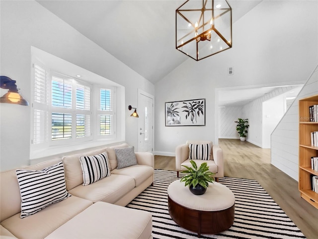 living room featuring an inviting chandelier, light hardwood / wood-style flooring, and high vaulted ceiling