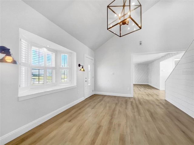 foyer entrance featuring high vaulted ceiling, a notable chandelier, and light hardwood / wood-style floors