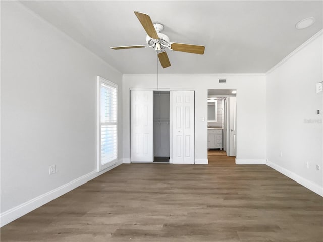 unfurnished bedroom featuring ornamental molding, dark wood-type flooring, ceiling fan, and ensuite bath