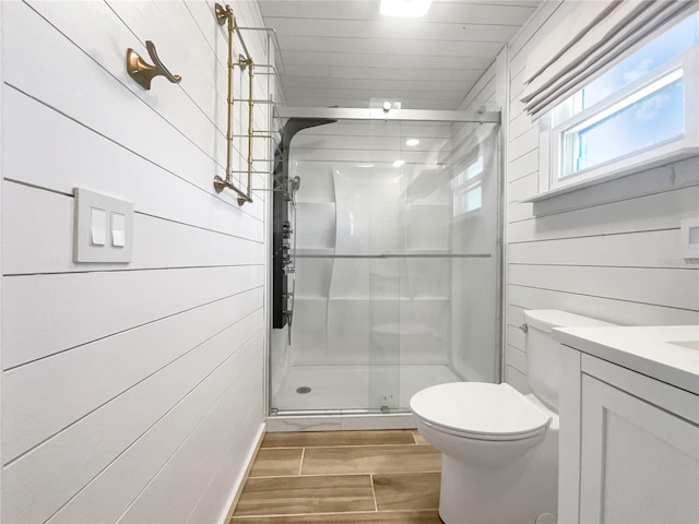 bathroom with walk in shower, vanity, wooden walls, and toilet