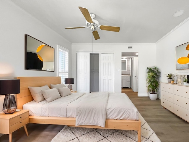 bedroom featuring ensuite bath, ceiling fan, ornamental molding, dark hardwood / wood-style flooring, and a closet