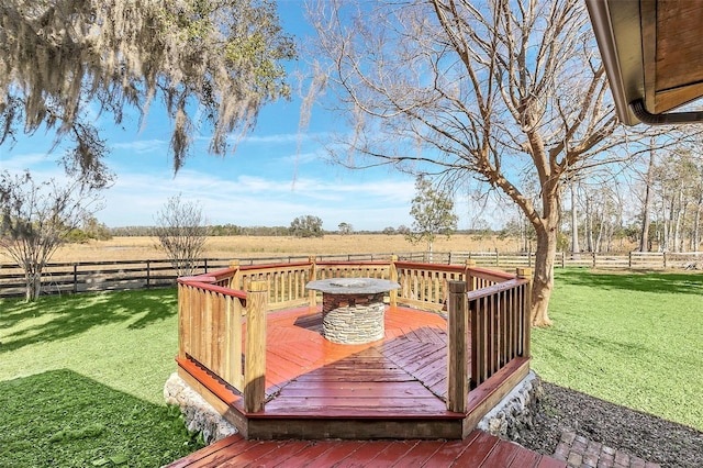 deck with an outdoor fire pit, a lawn, and a rural view