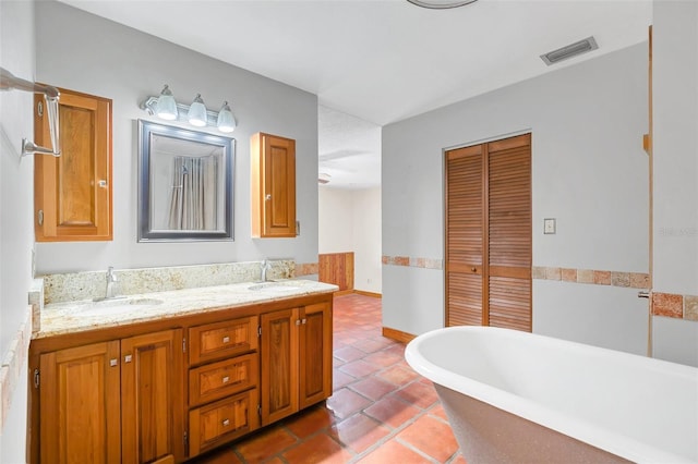 bathroom with tile patterned flooring, vanity, and a bath