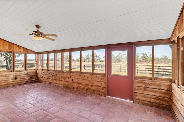 unfurnished sunroom featuring vaulted ceiling, a rural view, and ceiling fan