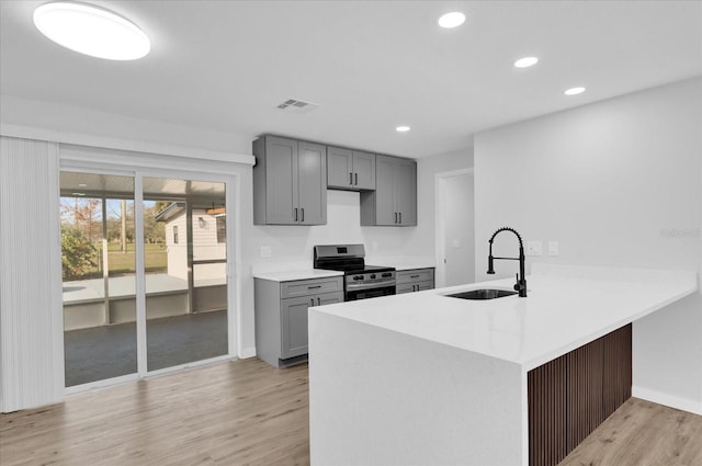 kitchen with sink, light hardwood / wood-style flooring, gray cabinetry, stainless steel electric stove, and kitchen peninsula