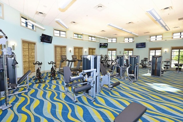 exercise room with carpet and a towering ceiling