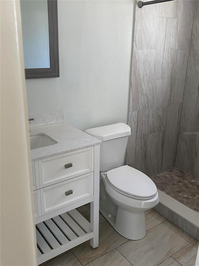 bathroom featuring vanity, toilet, and tiled shower