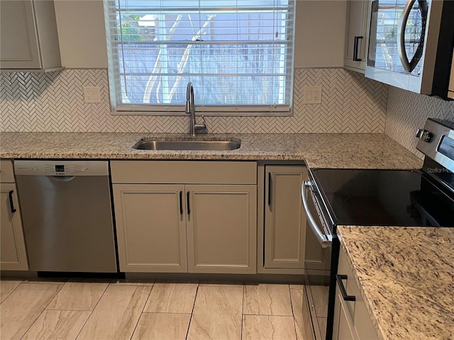 kitchen with stainless steel appliances, a healthy amount of sunlight, sink, and light stone counters