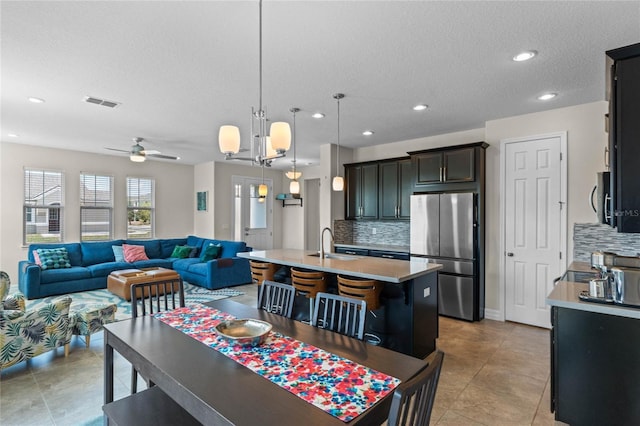 dining space featuring light tile patterned flooring, sink, ceiling fan, and a textured ceiling