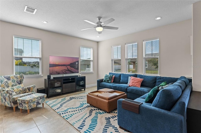 living room with tile patterned flooring, ceiling fan, and a textured ceiling