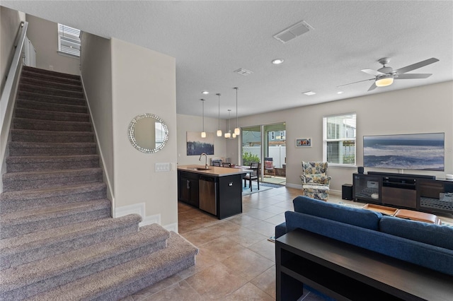 tiled living room featuring sink, a textured ceiling, and ceiling fan