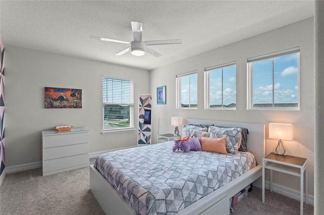 carpeted bedroom featuring ceiling fan and a textured ceiling