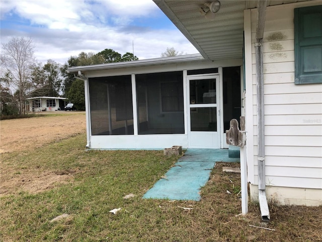 view of side of home with a sunroom and a lawn