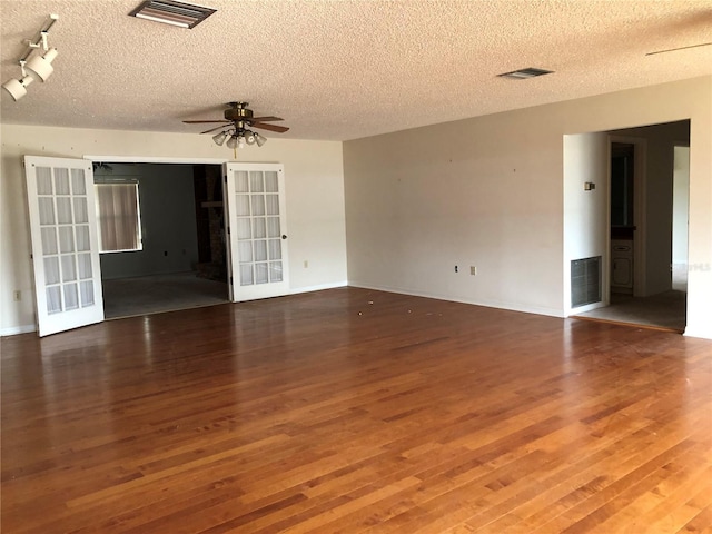 unfurnished room featuring french doors, a textured ceiling, track lighting, dark hardwood / wood-style floors, and ceiling fan