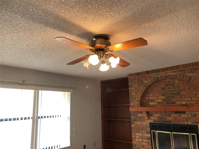 room details with ceiling fan, a brick fireplace, and a textured ceiling