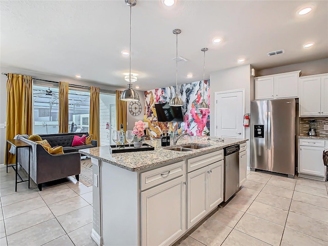 kitchen featuring sink, white cabinetry, appliances with stainless steel finishes, an island with sink, and pendant lighting