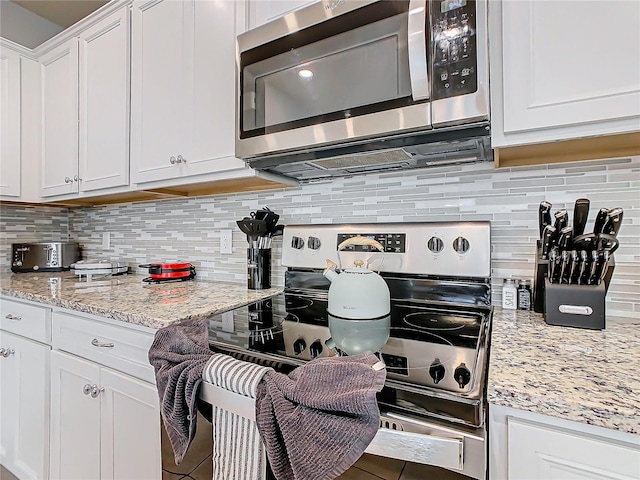 kitchen with white cabinetry, appliances with stainless steel finishes, light stone counters, and decorative backsplash