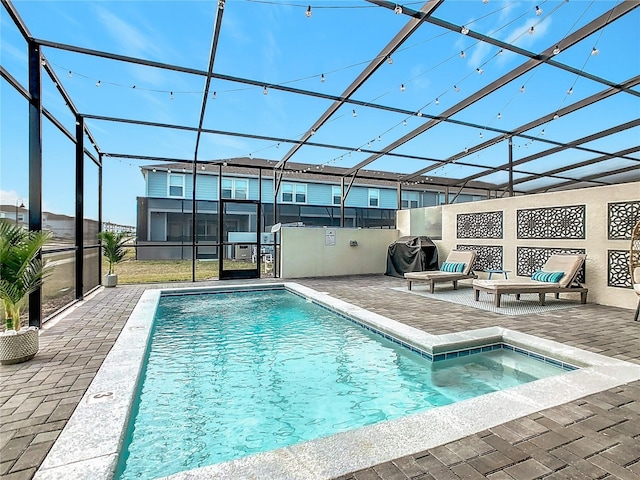 view of pool featuring a grill, glass enclosure, and a patio area