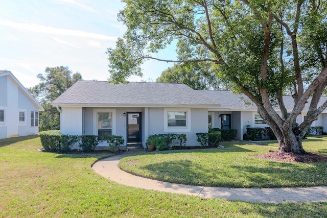 ranch-style home with roof with shingles and a front lawn