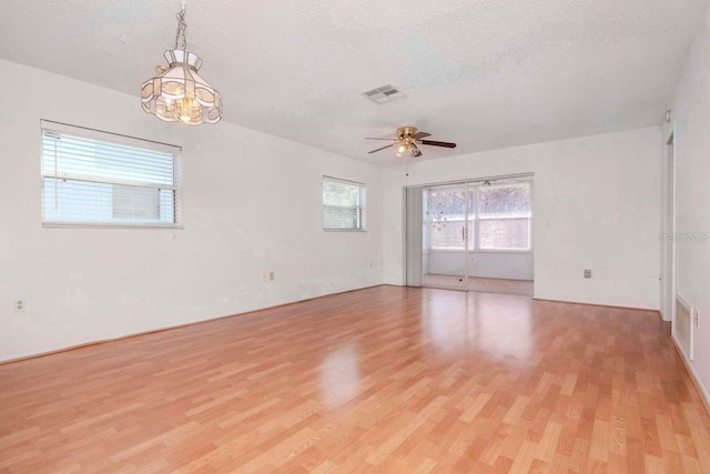 spare room featuring light wood finished floors, a ceiling fan, visible vents, and a textured ceiling