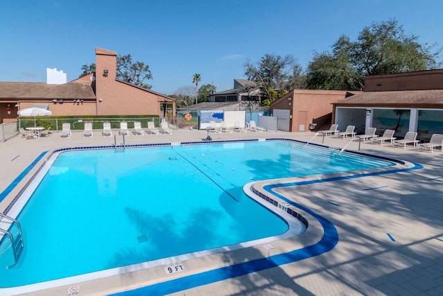 community pool with a patio area and fence