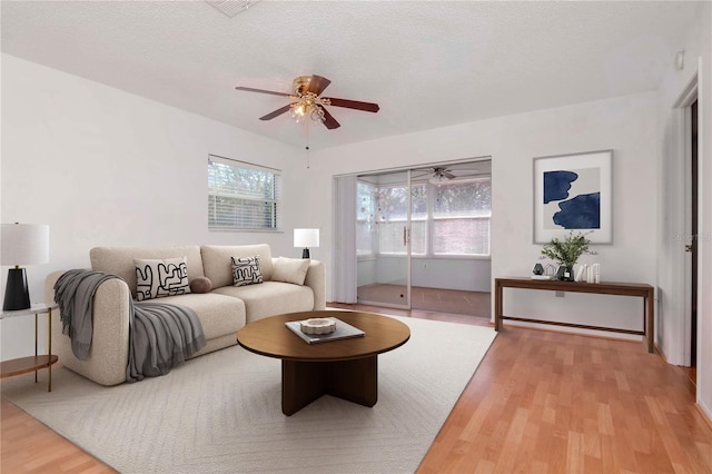 living room featuring a textured ceiling, light wood-style flooring, and a ceiling fan