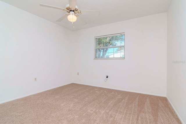 spare room featuring baseboards, a textured ceiling, a ceiling fan, and light colored carpet