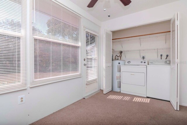 laundry room with washing machine and clothes dryer, light colored carpet, water heater, ceiling fan, and laundry area