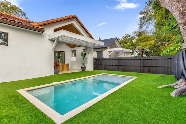 rear view of property with a yard and a fenced in pool