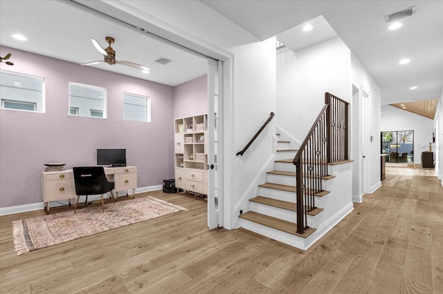 stairway with lofted ceiling, a wealth of natural light, wood-type flooring, and ceiling fan