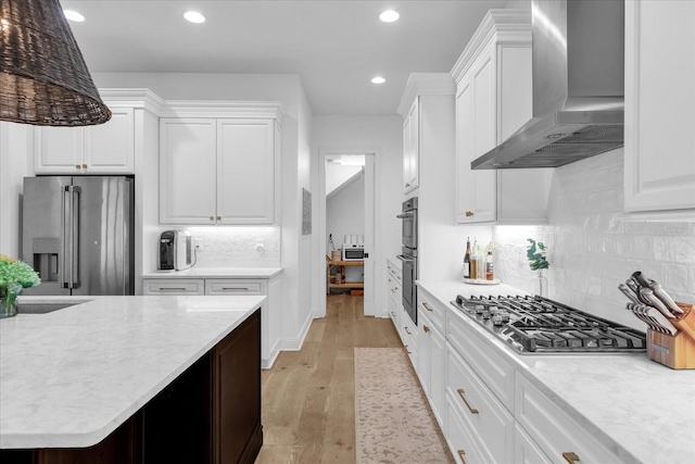 kitchen with stainless steel appliances, white cabinets, light wood-type flooring, and wall chimney exhaust hood