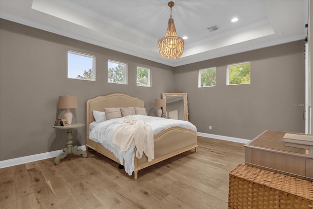 bedroom featuring a raised ceiling, crown molding, and light wood-type flooring