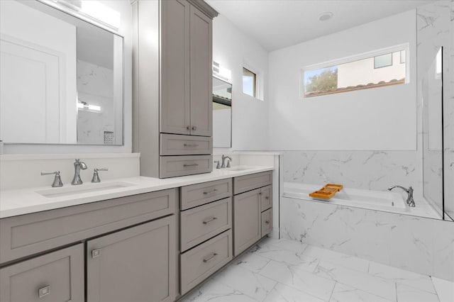 bathroom featuring tiled tub and vanity