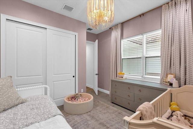 bedroom with light colored carpet, a chandelier, and a closet