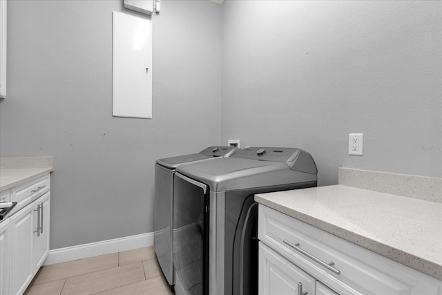 laundry room featuring cabinets, washer and clothes dryer, and light hardwood / wood-style flooring