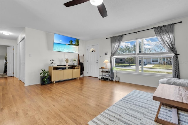 living area with light wood-style floors and a ceiling fan