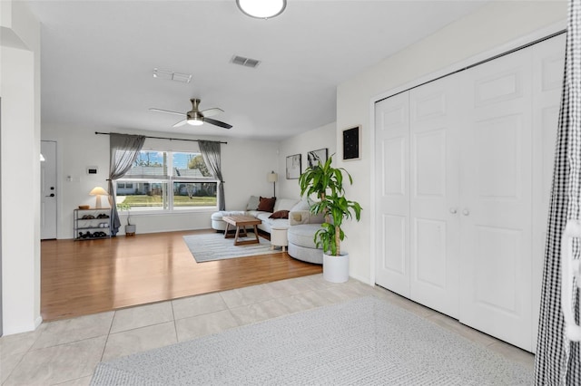 living area featuring light tile patterned floors, ceiling fan, and visible vents