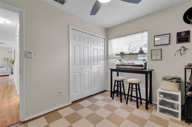 office space with a textured ceiling, ceiling fan, visible vents, and baseboards