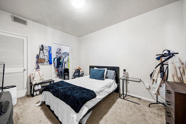 bedroom with a walk in closet, light carpet, a textured ceiling, and a closet