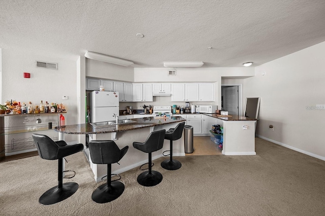 kitchen featuring a breakfast bar, sink, a center island, light carpet, and white appliances